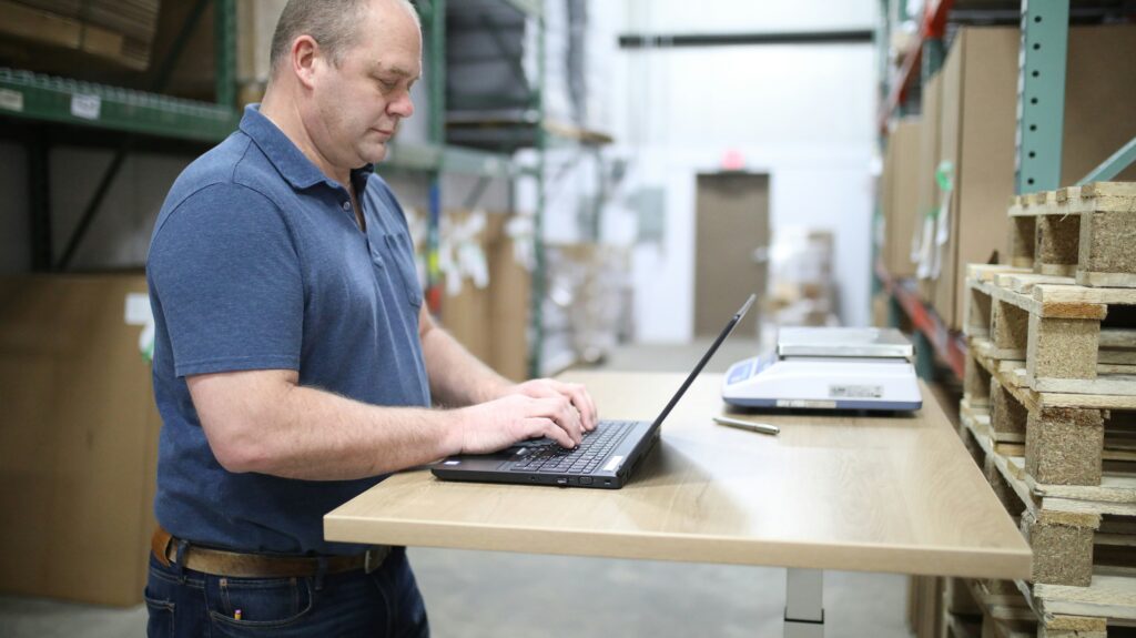 A person is working on a laptop in a warehouse.
